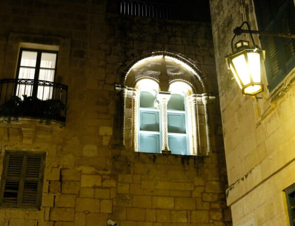 Old, ornate windows and a lamp shining at night