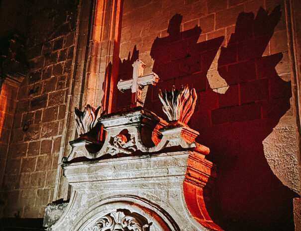The entrance to an ossary seen at night, with a shadow cast on the wall behind it