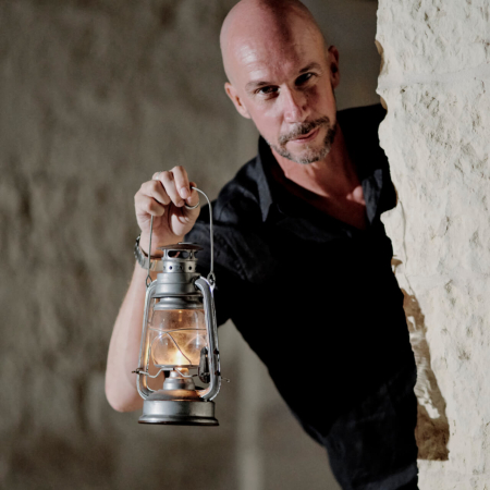 A man holding a lantern looking around a corner